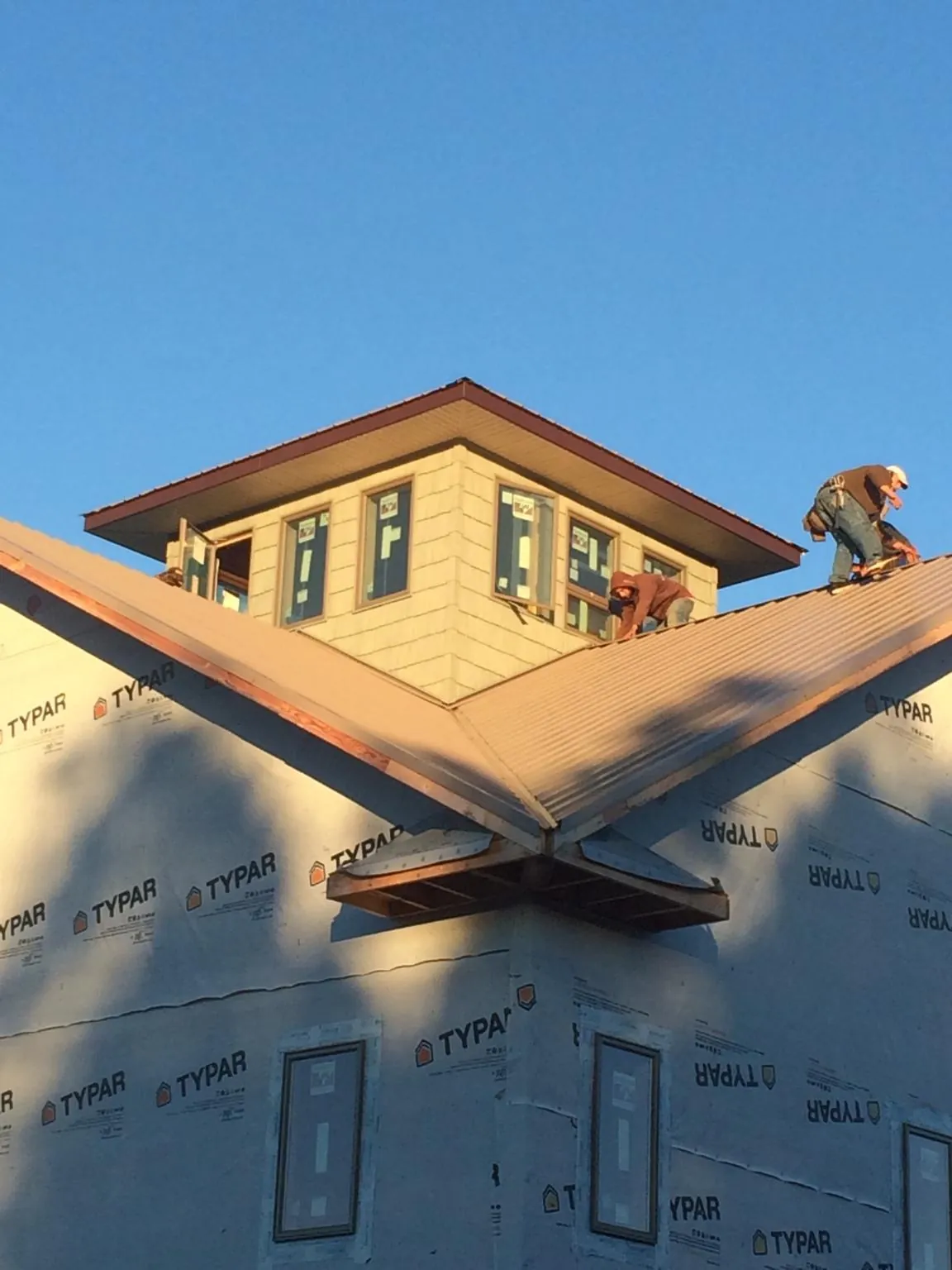 Roofers working around a rooftop cupola on a new metal roof at sunset — Roof Waterproofing in Milton by Roofing Brothers